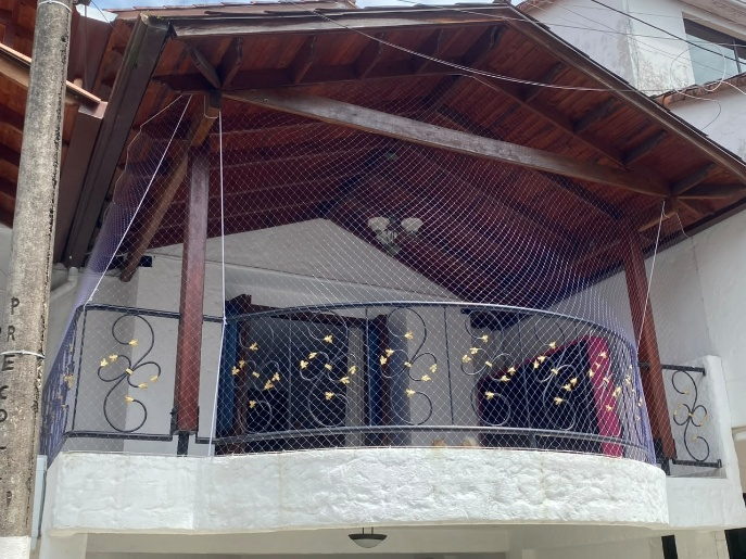 Balcon de casa con techo en madera cerrado con malla de seguridad