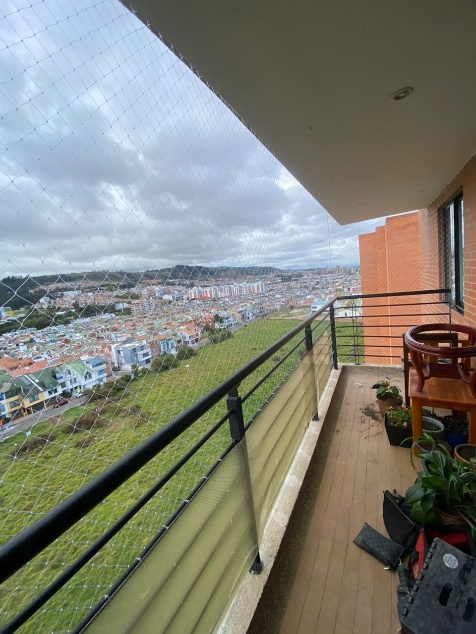 Balcon alargado con malla de seguridad y vista a la ciudad